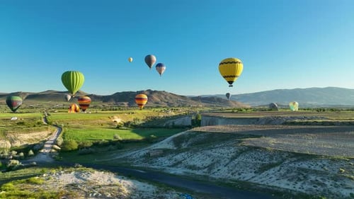 Hot air balloons fly over the mountainous landscape of Cappadocia, Turkey.