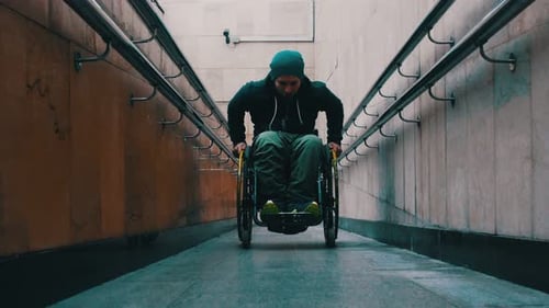 Disabled Man in Wheelchair Getting Up on the Long Special Ramp Sometimes Leaning on the Railing