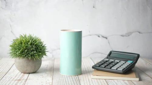 Hand Puts Money in Coin Box on Desk