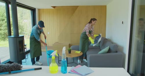 Positive Smiling Professional Cleaners Doing Cleanup in Ordinary Apartment