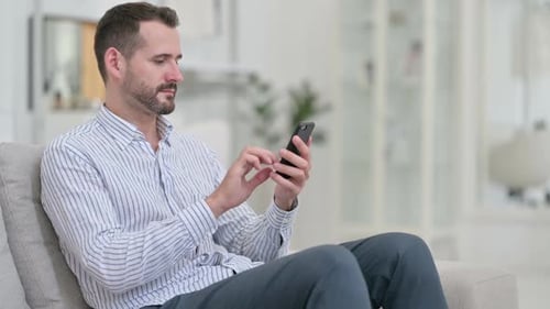 Man Using Smartphone While Sitting on a Couch