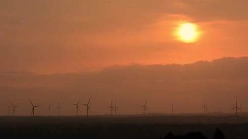 Wunderschöner Sonnenuntergang mit dem bunten bewölkten Himmel mit sich drehenden Windkraftanlagen für elektrische Energie