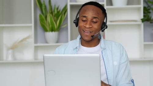 Young Adult Wearing Headset Talking to Laptop