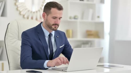 Serious Businessman Using Laptop in Office