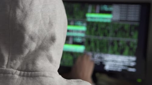 Hacker tries to hack into the system. A female hacker works at a computer at night in the dark.