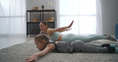 Woman and Child Doing Back Extension Exercise at Home