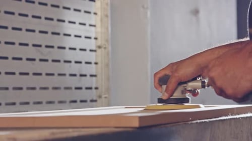 Slow motion of a worker polishing a cabinet door in a furniture factory