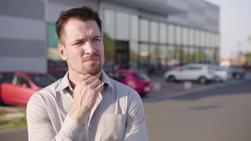 A Young Caucasian Man Thinks About Something in an Urban Area