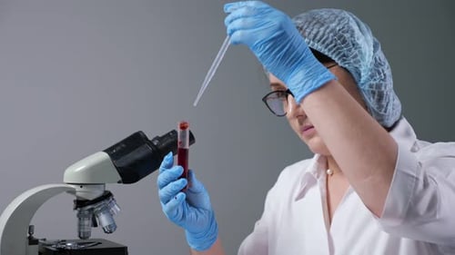 Woman Scientist Adds Liquid Sample in Laboratory
