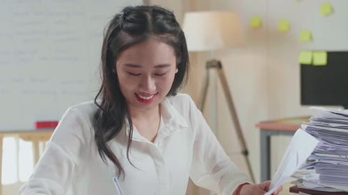 Close Up Of Smiling Asian Woman Enjoys Working With Documents At The Office
