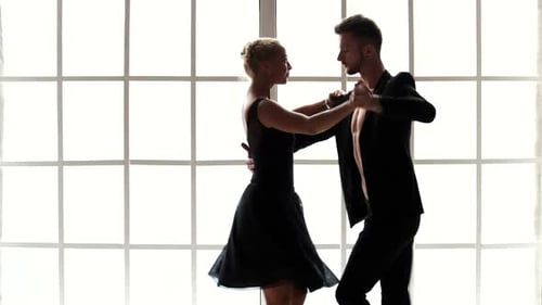 Elegant Young Couple Dances in Silhouette by Window