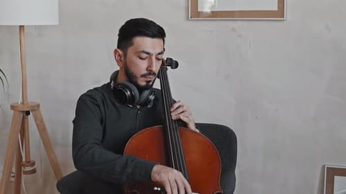 Man Plays Cello in Bright, Airy Living Room
