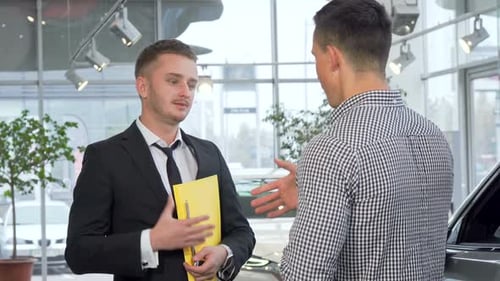 Car Salesman Shakes Hands with Customer in Dealership