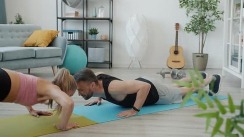 Slow Motion of Young Man Training at Home with Girlfriend Doing Pushups Together Smiling