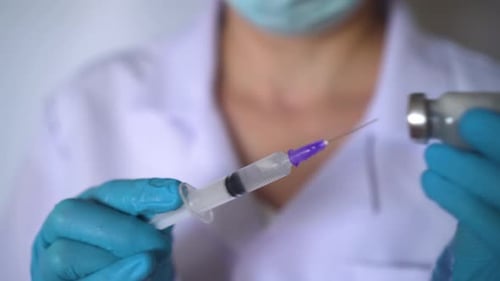 Medical Professional Draws Liquid into Syringe