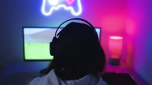 Person Playing Video Game in Neon Lit Room