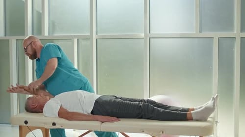 Physiotherapeut führt eine Therapiesitzung mit einem älteren Mann in einem Rehabilitationszentrum durch