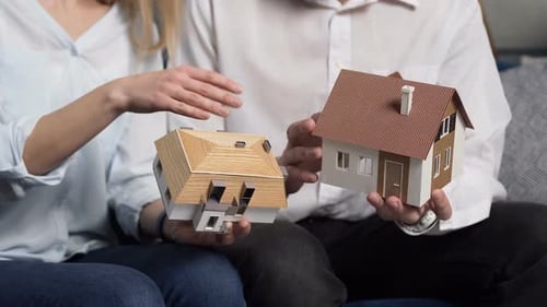 Close Up Shof of 3d Model of Two House in the Man and Woman Hands.