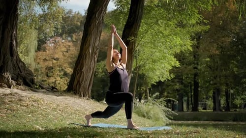 Wide View of Woman Sitting on Yoga Mat and Practicing Yoga Stretching Exercise Outdoors in Sunny Day