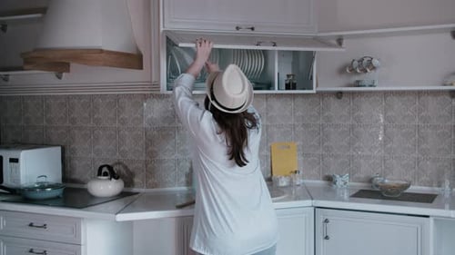 Person in Kitchen Opening Cabinets and Stretching