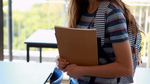 Smiling Student Holding Notebook in Classroom