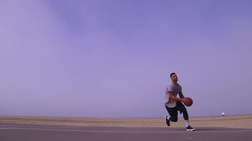 A man does a slam dunk while playing one-on-one basketball hoops on a beach court