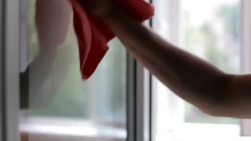 Cleaning service worker washes windows using window cleaner.
