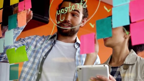 Male and female executives discussing over sticky notes