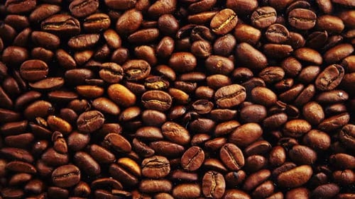Fallende Kaffeebohnen auf schwarzem Hintergrund.