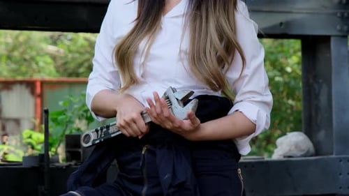 Asian female engineering worker with industrial wrench in workshop.
