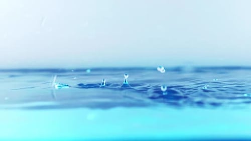 The clean water surface in slow motion fills the screen with water splashing shop the water drop and
