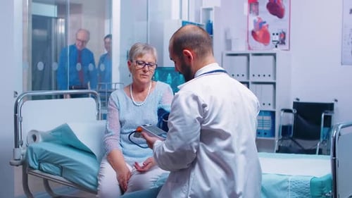 Doctor Checking Blood Pressure of Senior Woman in Hospital