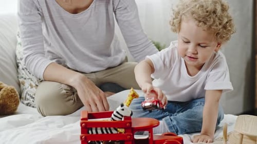 Little Child Plays with Toys on Bed