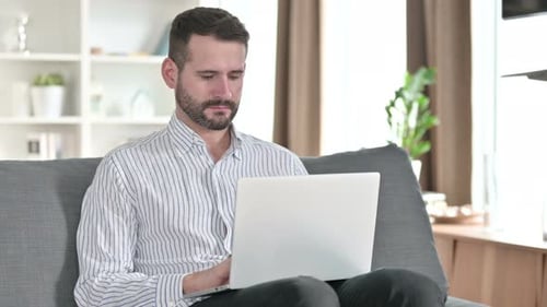 Man Working on Laptop on Couch at Home