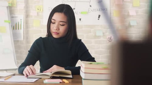 Young Asian female college student concentrating on reading book