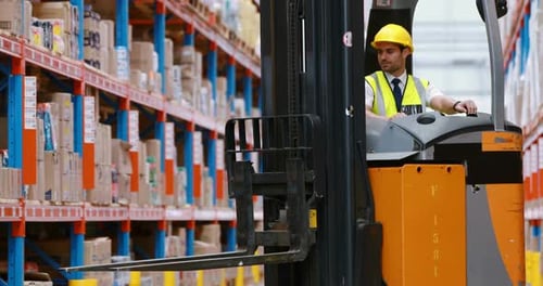 Male warehouse worker using forklift truck