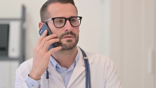 Doctor Talking on Mobile Phone in Hospital Office