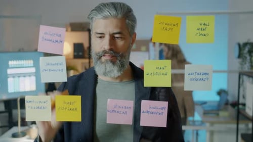 Erfahrener Geschäftsmann, der mit bunten Haftnotizen arbeitet, konzentriert sich auf kreative Aktivitäten in