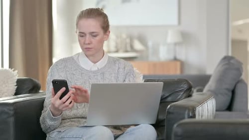 Woman Uses Laptop and Phone on Couch