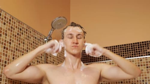 Young Man Washing Hair with Shampoo in Shower