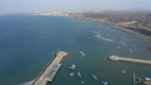 Aerial view of a small boat leaving a port and heading towards the open ocean