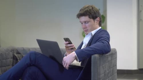Young Adult Man Using Phone and Laptop
