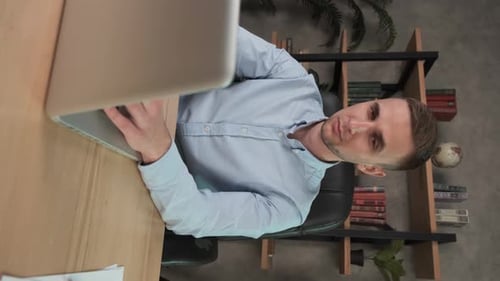 Vertical, Young Smiling Man Employee Works in the Office at the Computer, Male Office Worker Looking