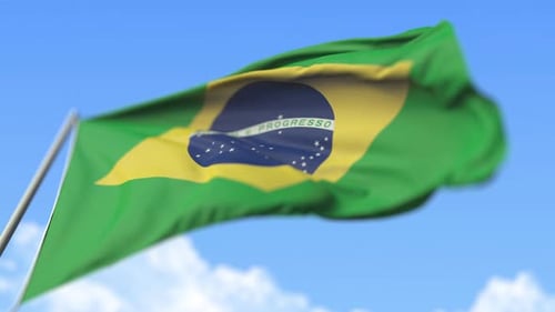 Brazilian Flag Waving in Wind Against Blue Sky