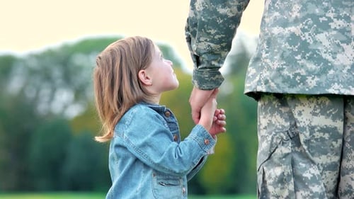 Child Holding Hands With a Soldier Outdoors