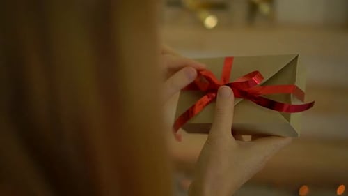 Hands Untying Red Ribbon on Christmas Gift