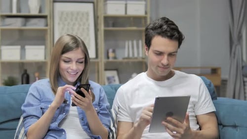 Young Adults Relaxing on Couch with Mobile Technology