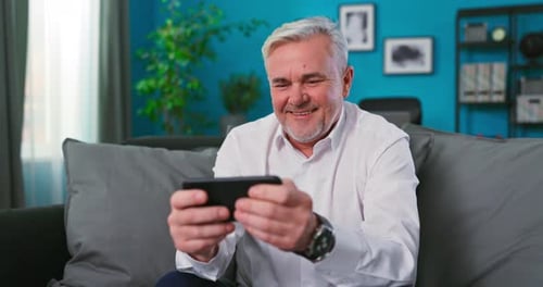Senior Man Using Smartphone on Couch at Home