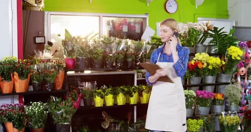 Female florist taking order on mobile phone in flower shop