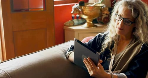 Woman Using Tablet While Relaxing on Couch